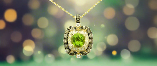 A green peridot necklace in 14K yellow gold with a bokeh background