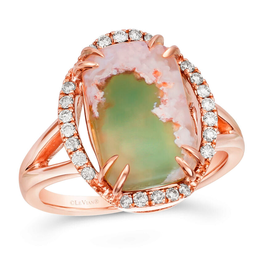 A rose gold ring featuring a large natural agate stone with green and pink patterns, surrounded by a halo of small clear stones, on a white background.