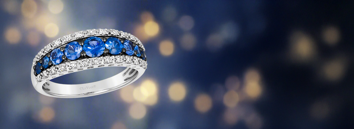 14K Vanilla Gold Le Vian ring with blue Sapphires on a blurred bokeh effect background.