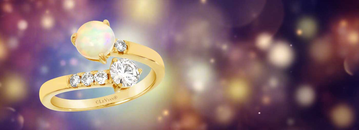 Gold ring with opal and diamonds on a blurred background
